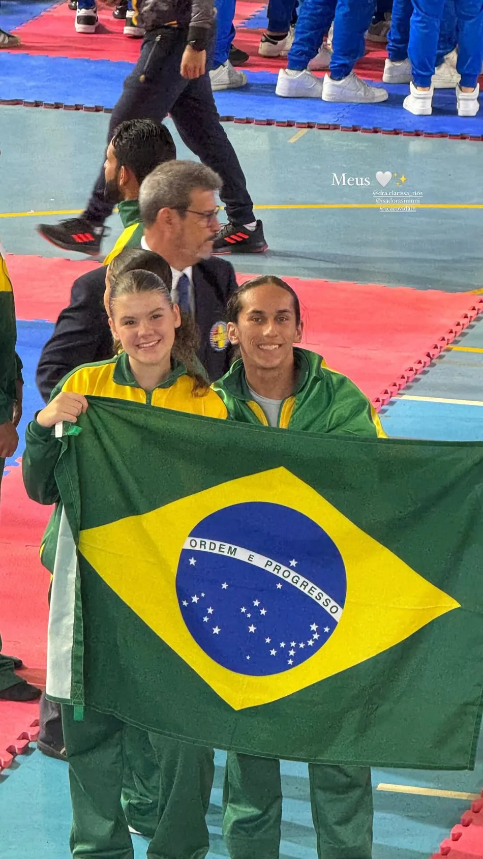 Atletas brasileiros segurando a bandeira do Brasil